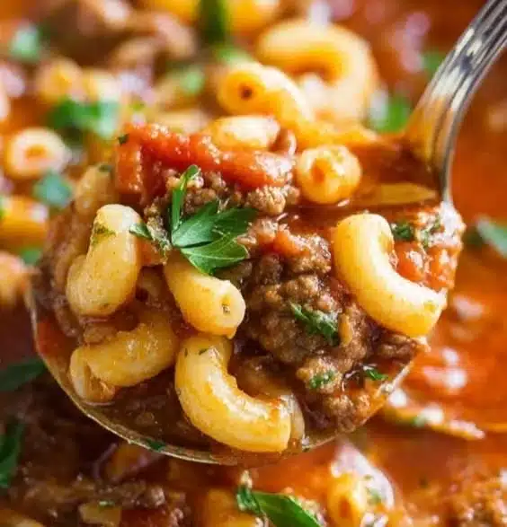 Bowl of beef and macaroni soup garnished with parsley