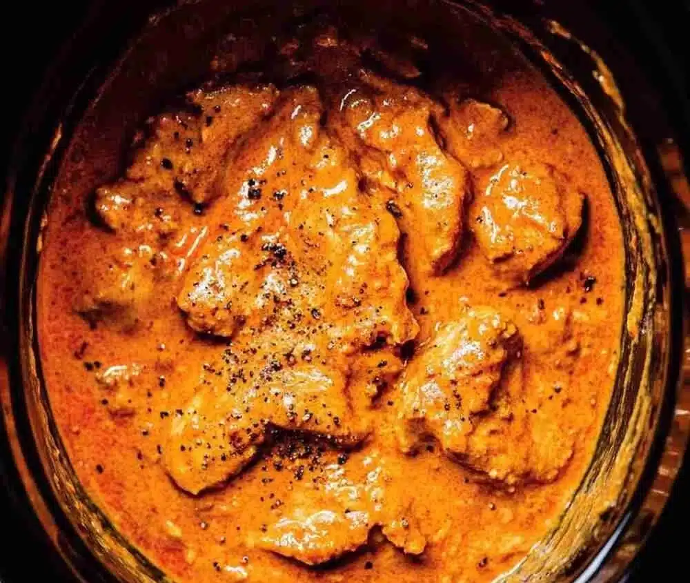 Bowl of easy Crockpot Chicken Tikka Masala served with rice and garnished.