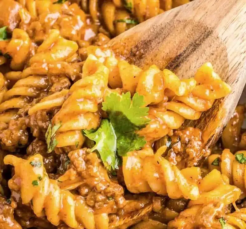 Delicious enchilada pasta topped with cheese and garnished with fresh herbs