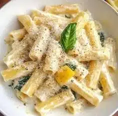 A plate of lemon pasta garnished with fresh herbs and lemon zest