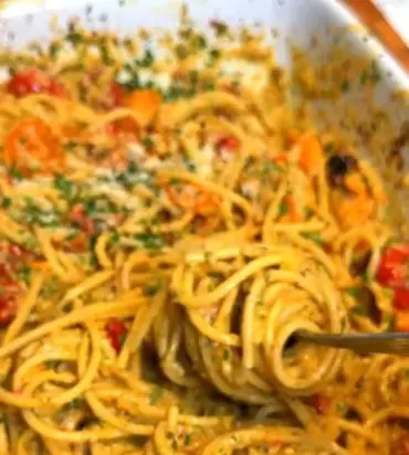 Pesto pasta with roasted tomatoes in a bowl, garnished with basil.