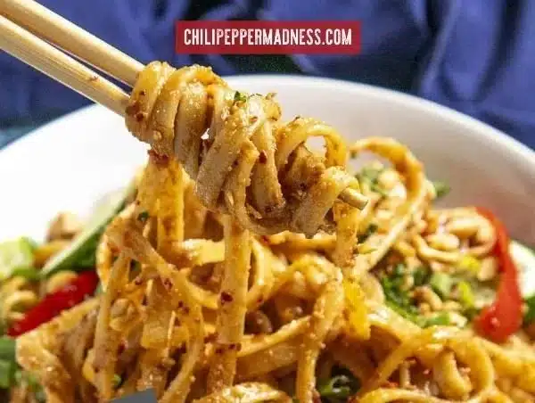Delicious plate of Thai Peanut Noodles garnished with cilantro and lime.